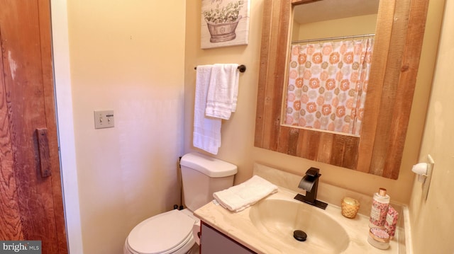 bathroom with toilet, a shower with shower curtain, and vanity