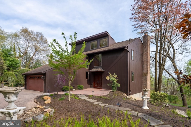 view of front of house with a garage, a chimney, and driveway