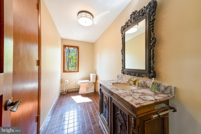 bathroom featuring baseboards, vanity, and toilet