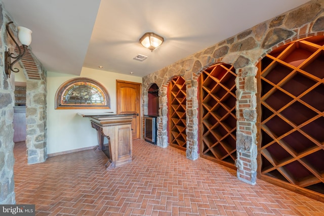 wine cellar featuring baseboards, visible vents, and brick floor