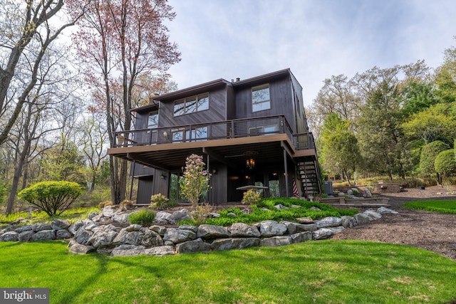 back of house featuring stairway, a deck, and a lawn