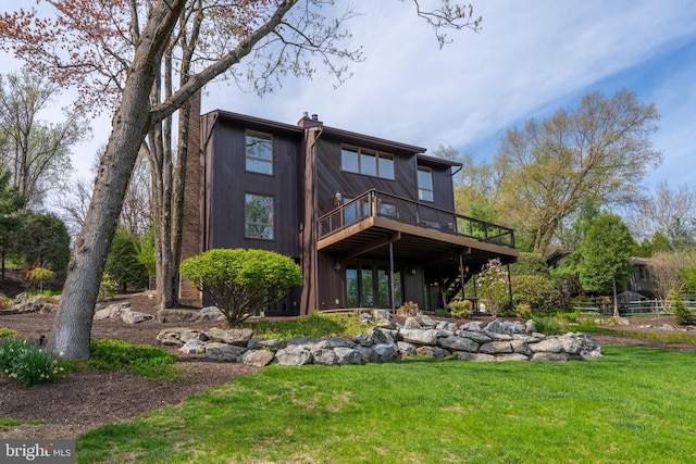 rear view of house with a wooden deck, a yard, and a chimney