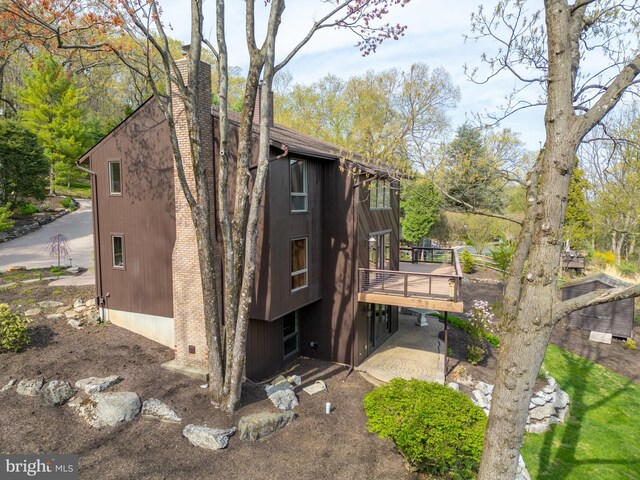 view of side of home featuring a chimney and a deck