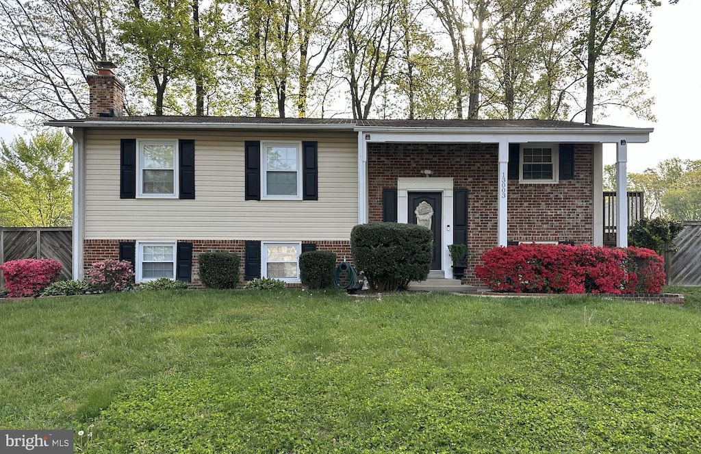split foyer home with a chimney, a front yard, and brick siding