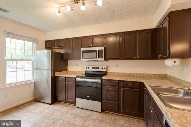 13830 Lord Fairfax Pl, Upper Marlboro, MD 20772 - kitchen with appliances with stainless steel finishes, a sink, dark brown cabinets, light countertops, and a textured ceiling