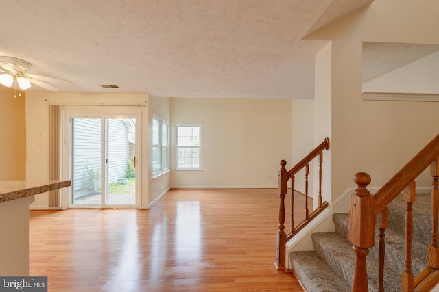 13830 Lord Fairfax Pl, Upper Marlboro, MD 20772 - unfurnished living room with light wood-style floors, a textured ceiling, baseboards, a ceiling fan, and stairway