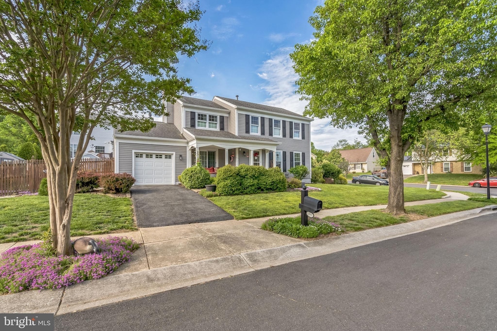traditional home featuring a garage, a front lawn, fence, and driveway