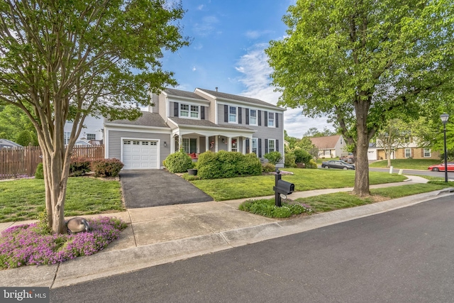 traditional home featuring a garage, a front lawn, fence, and driveway