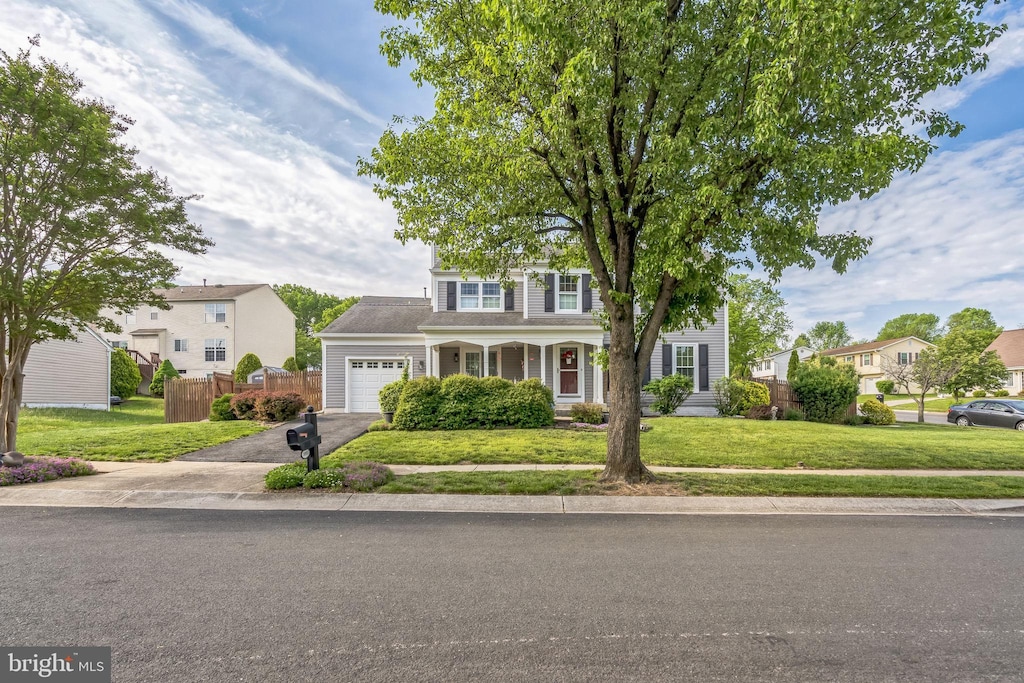view of front of home featuring fence, aphalt driveway, a front lawn, and a garage