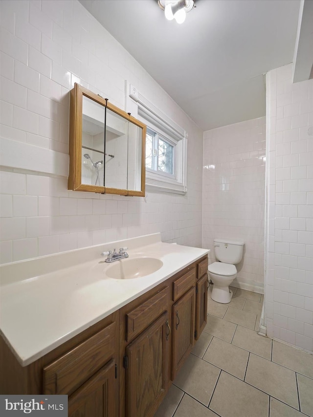 full bathroom with tile walls, toilet, walk in shower, tile patterned floors, and vanity