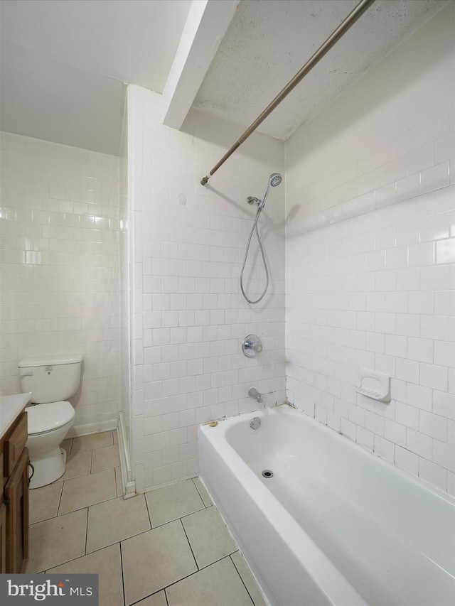 bathroom with tile walls, toilet, tile patterned floors, vanity, and shower / washtub combination