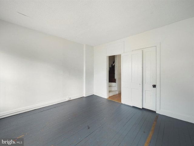 unfurnished bedroom featuring a closet, dark wood-type flooring, and baseboards