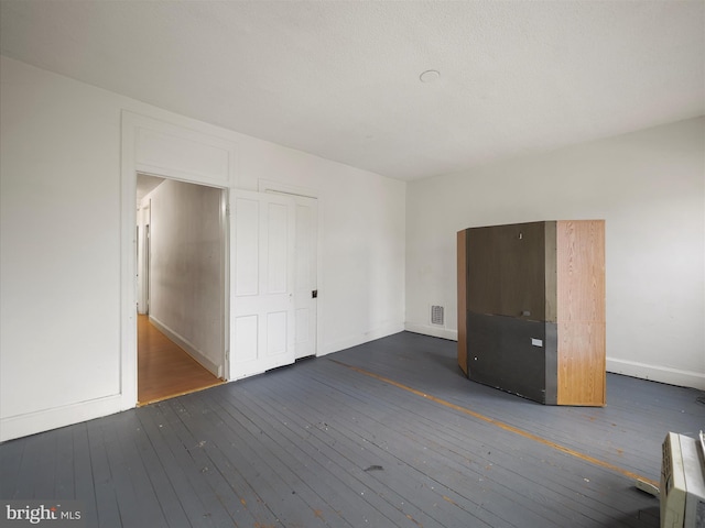 unfurnished bedroom with baseboards, hardwood / wood-style floors, and visible vents