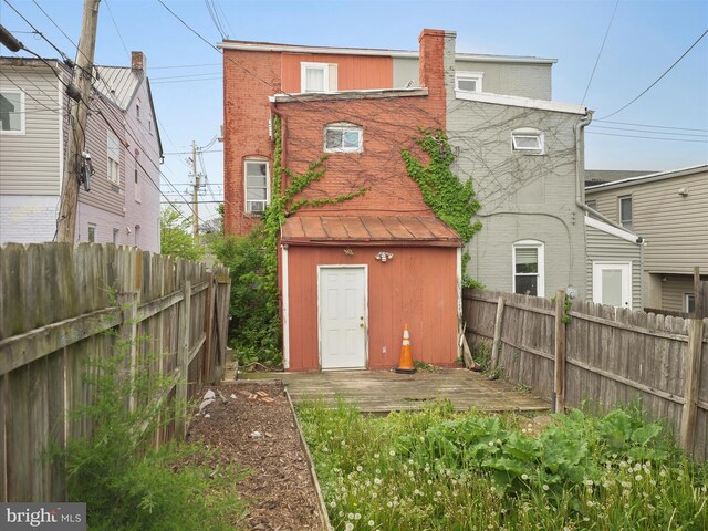 rear view of property featuring an outbuilding, a deck, a fenced backyard, and a shed