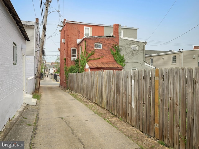 view of side of property featuring concrete driveway and fence