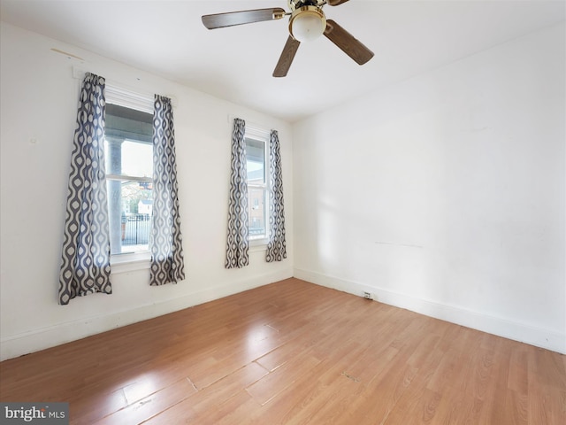 empty room with light wood finished floors, baseboards, and ceiling fan
