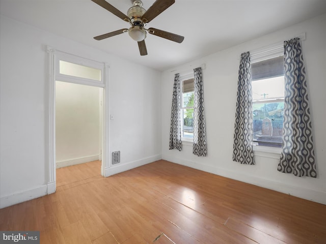 unfurnished room featuring a ceiling fan, baseboards, light wood finished floors, and visible vents
