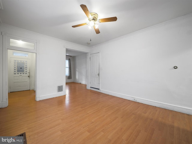 empty room featuring crown molding, light wood-type flooring, visible vents, and a ceiling fan