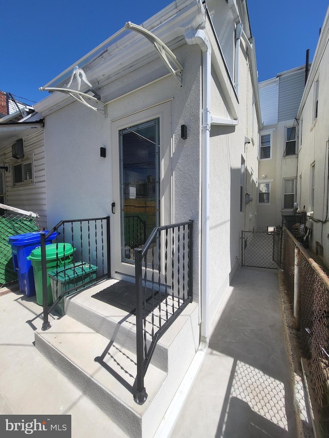 doorway to property featuring fence, a patio area, and stucco siding
