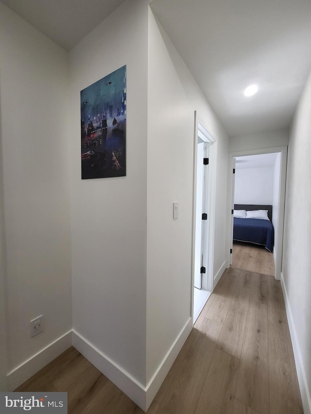 corridor with baseboards and wood finished floors