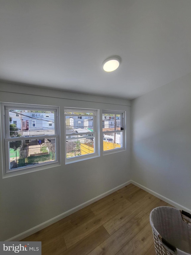empty room with plenty of natural light, baseboards, and wood finished floors