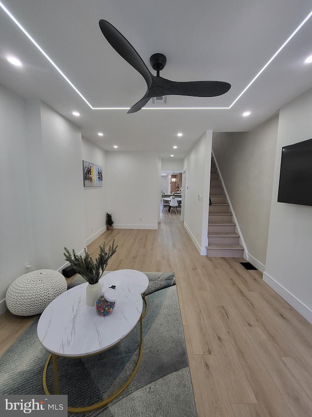 living room featuring stairs, a ceiling fan, baseboards, recessed lighting, and wood finished floors