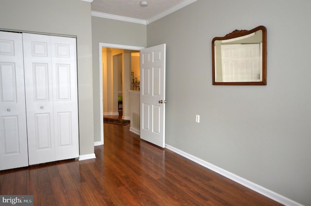 unfurnished bedroom featuring ornamental molding, a closet, baseboards, and wood finished floors