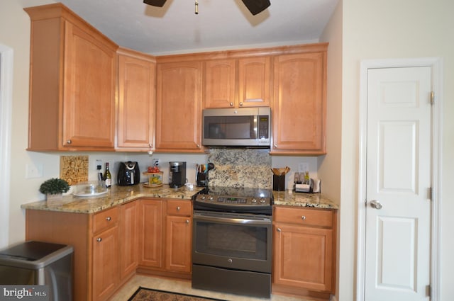 kitchen featuring light stone countertops, stainless steel appliances, and a ceiling fan