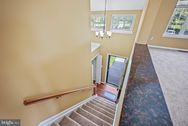 carpeted entryway featuring stairs, baseboards, an inviting chandelier, and visible vents