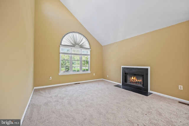 unfurnished living room featuring visible vents, a fireplace with flush hearth, baseboards, high vaulted ceiling, and carpet flooring