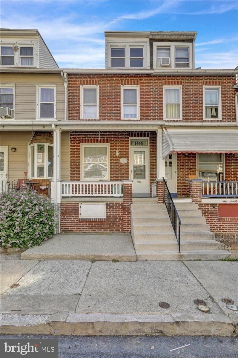 multi unit property with a porch, brick siding, and cooling unit