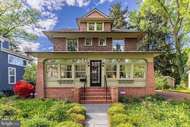 american foursquare style home with central AC unit, entry steps, and brick siding