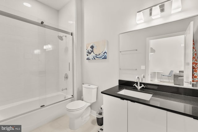 bathroom featuring tile patterned flooring, vanity, toilet, enclosed tub / shower combo, and baseboards