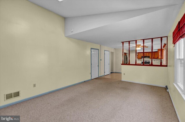 unfurnished room with carpet floors, baseboards, visible vents, and lofted ceiling