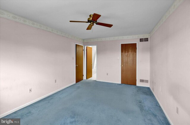 empty room with carpet floors, a ceiling fan, baseboards, and visible vents
