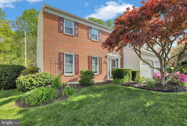 colonial-style house featuring brick siding and a front yard