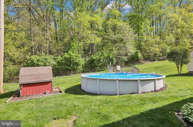 outdoor pool featuring an outbuilding, a yard, a shed, and a wooded view