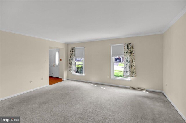 empty room with crown molding, carpet flooring, visible vents, and baseboards