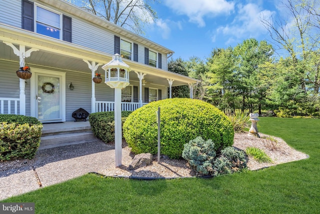 view of exterior entry featuring a lawn and a porch