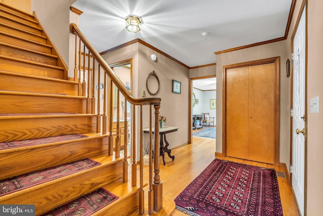 foyer featuring ornamental molding, wood finished floors, and stairway