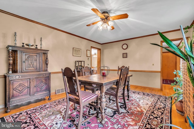 dining space with visible vents, crown molding, light wood-style floors, and ceiling fan