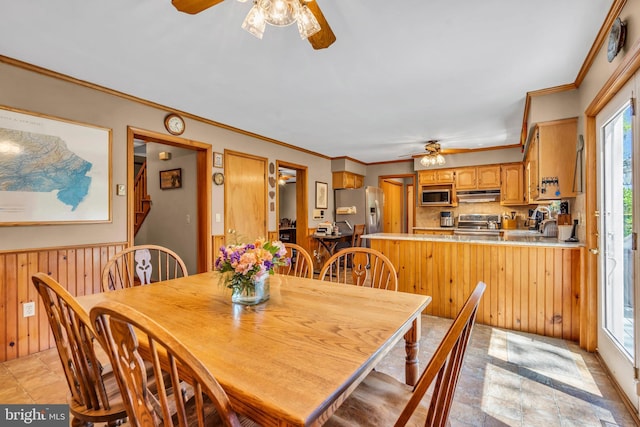 dining room featuring plenty of natural light, wood walls, and ceiling fan