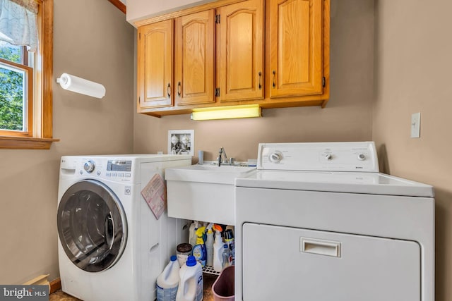 clothes washing area featuring cabinet space, separate washer and dryer, and a sink