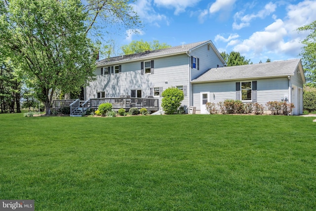 rear view of property featuring a lawn, a deck, an attached garage, and roof with shingles