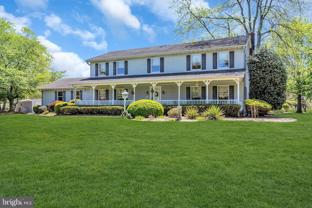 view of front of property with a porch, a chimney, and a front yard