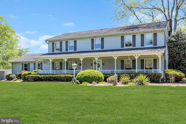 view of front of home with a porch, a chimney, and a front yard