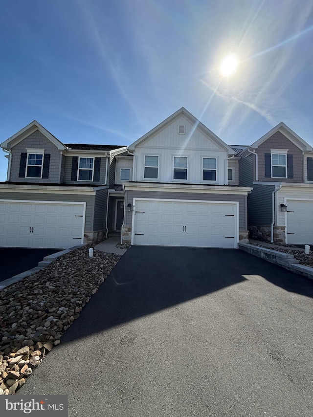 view of front of home featuring stone siding, aphalt driveway, an attached garage, and board and batten siding