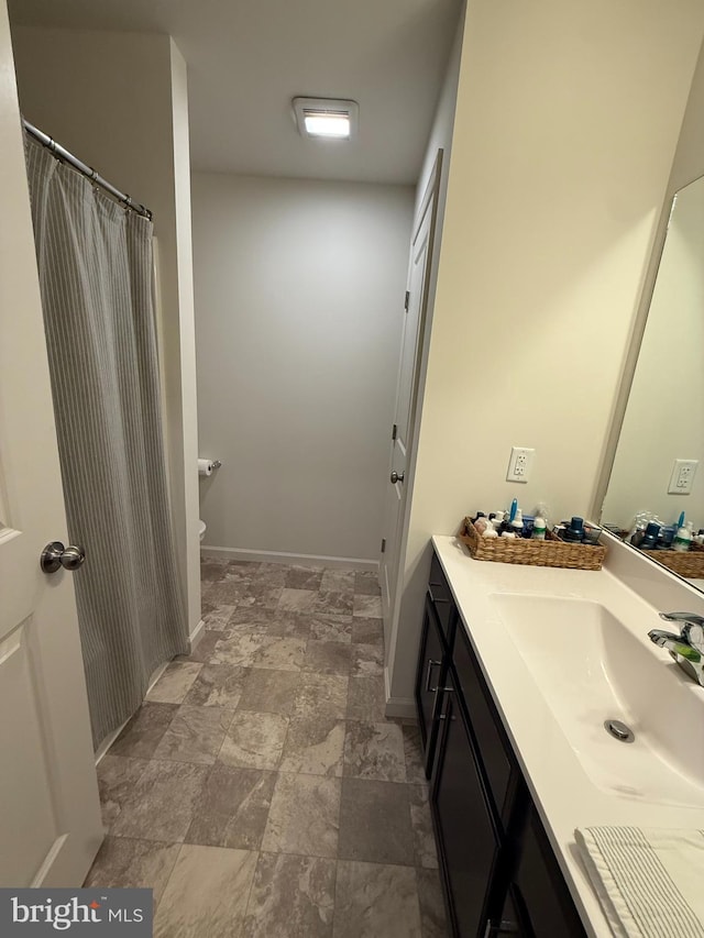 full bath featuring toilet, baseboards, vanity, and stone finish floor