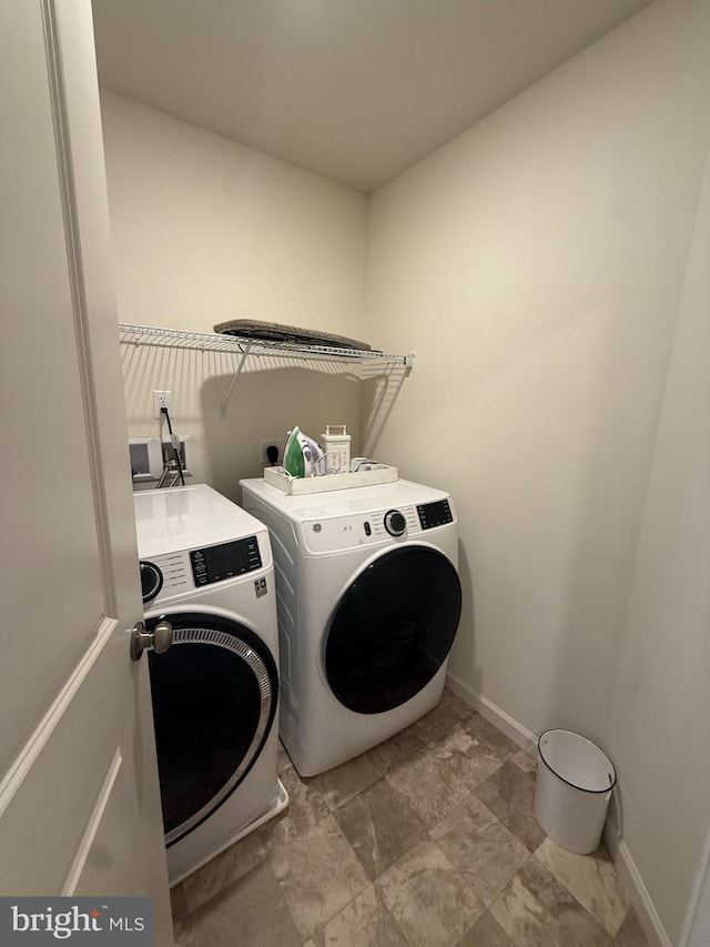 clothes washing area featuring baseboards, laundry area, and washer and clothes dryer