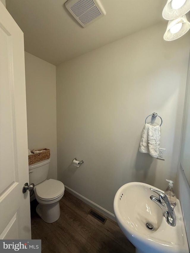 bathroom featuring a sink, toilet, visible vents, and wood finished floors